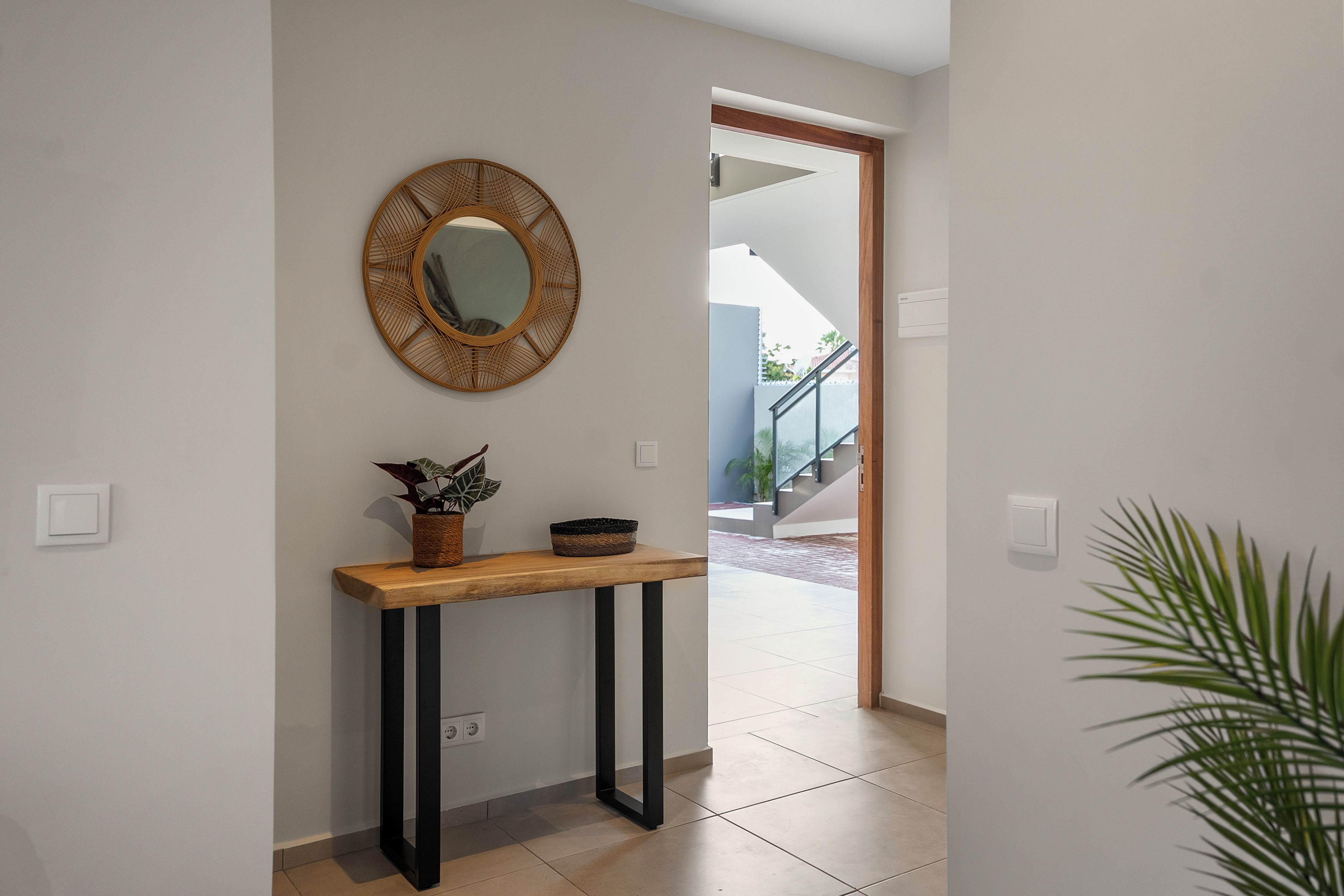 Un couloir avec une console en bois, un miroir et une plante en pot.