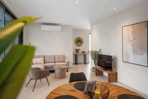 Uma sala de estar moderna com sofá, mesa de centro, TV e obras de arte.