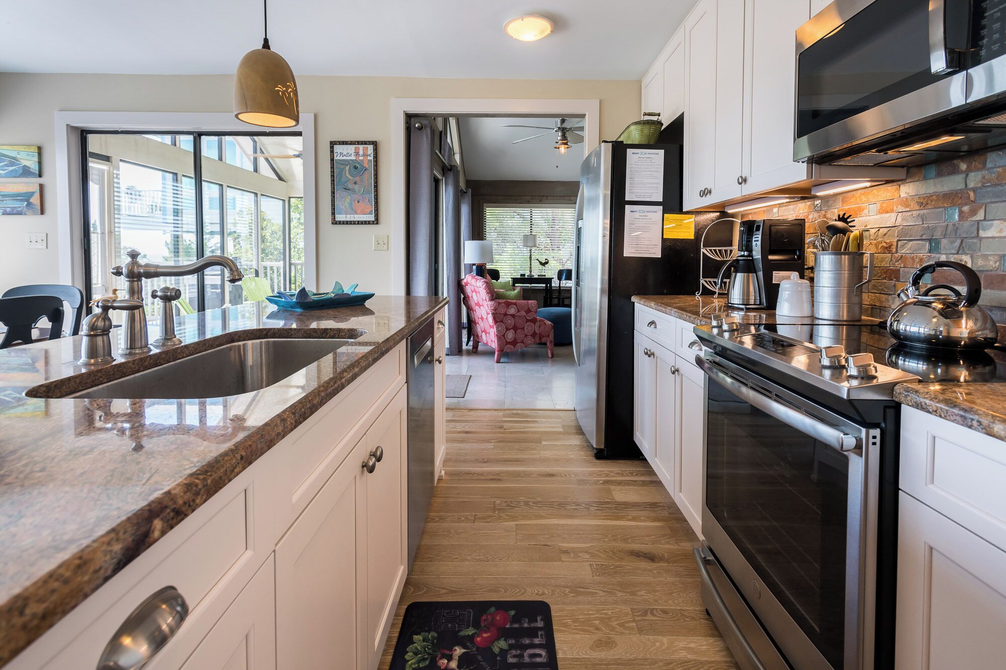 Una cocina moderna con encimera de granito, electrodomésticos de acero inoxidable y vistas al área de estar.