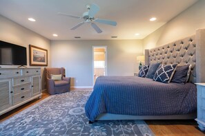 A bedroom with a bed, a dresser, a chair, a ceiling fan, and a television. - Gulf Front w/ Private Beach Access- Sea Turtle Cottage by Royal Destinations (Santa Rosa Beach)