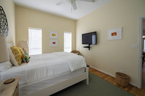 Ein Schlafzimmer mit einem Bett, einem Fernseher und Kunstwerken an der Wand.