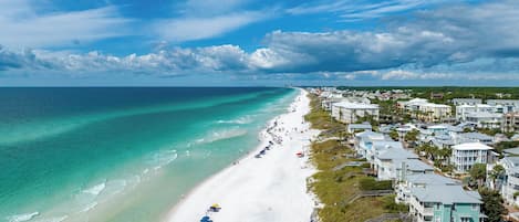 A coastal hotel with beachfront rooms, a sandy beach, and a clear view of the ocean.