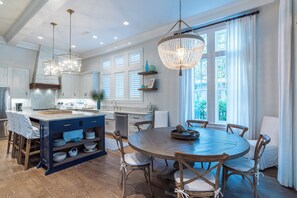 A spacious kitchen with a central island, wooden chairs around a round table, and large windows with curtains. - Private Pool, Steps From Beach & Seaside- Sunday Morning (Santa Rosa Beach)