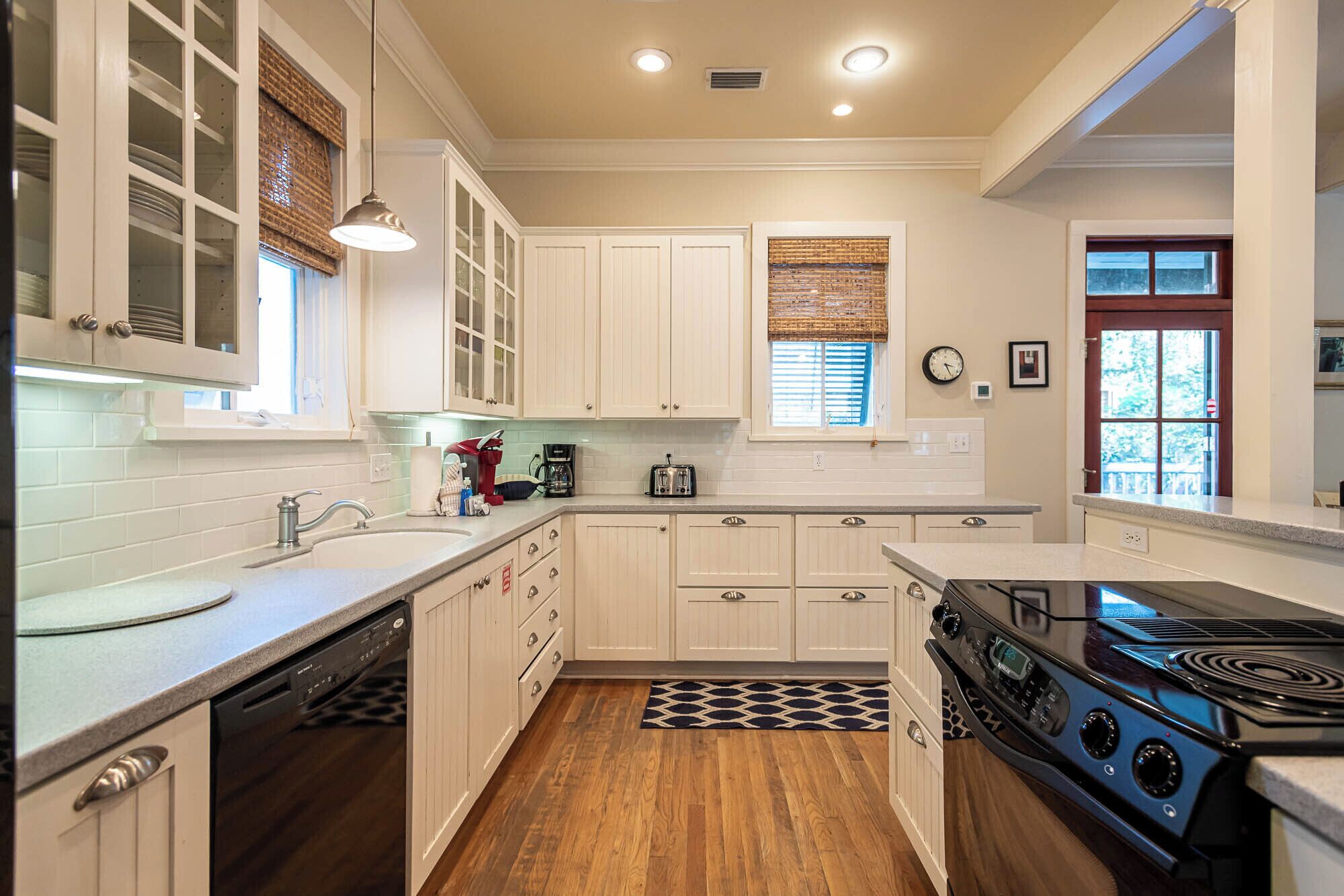 A kitchen with white cabinets, a dishwasher, a stove, and a clock on the wall.