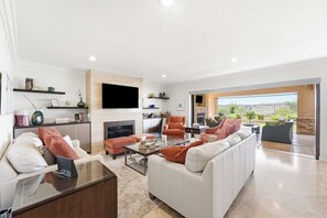A spacious living room with a fireplace, comfortable seating, and a view to the outside. - Classic California Retreat (Laguna Niguel)