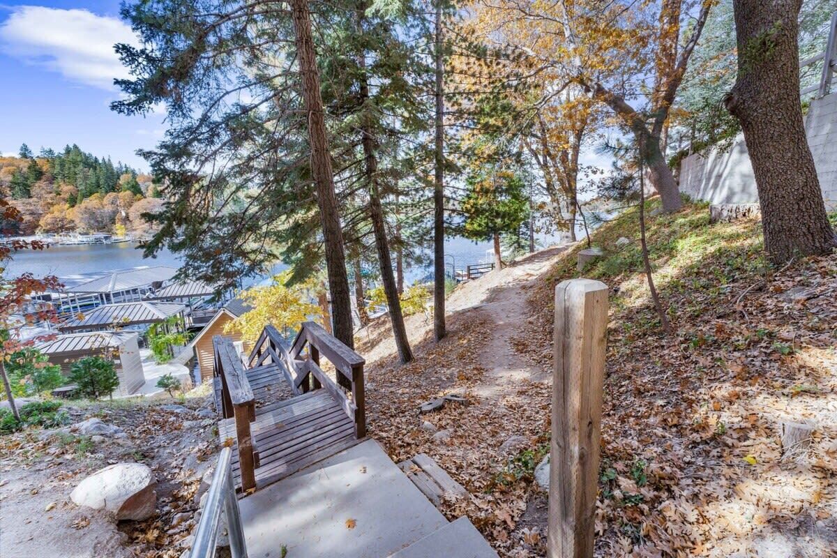 A wooden staircase leading down to a path with a view of a lake and buildings in the background.
