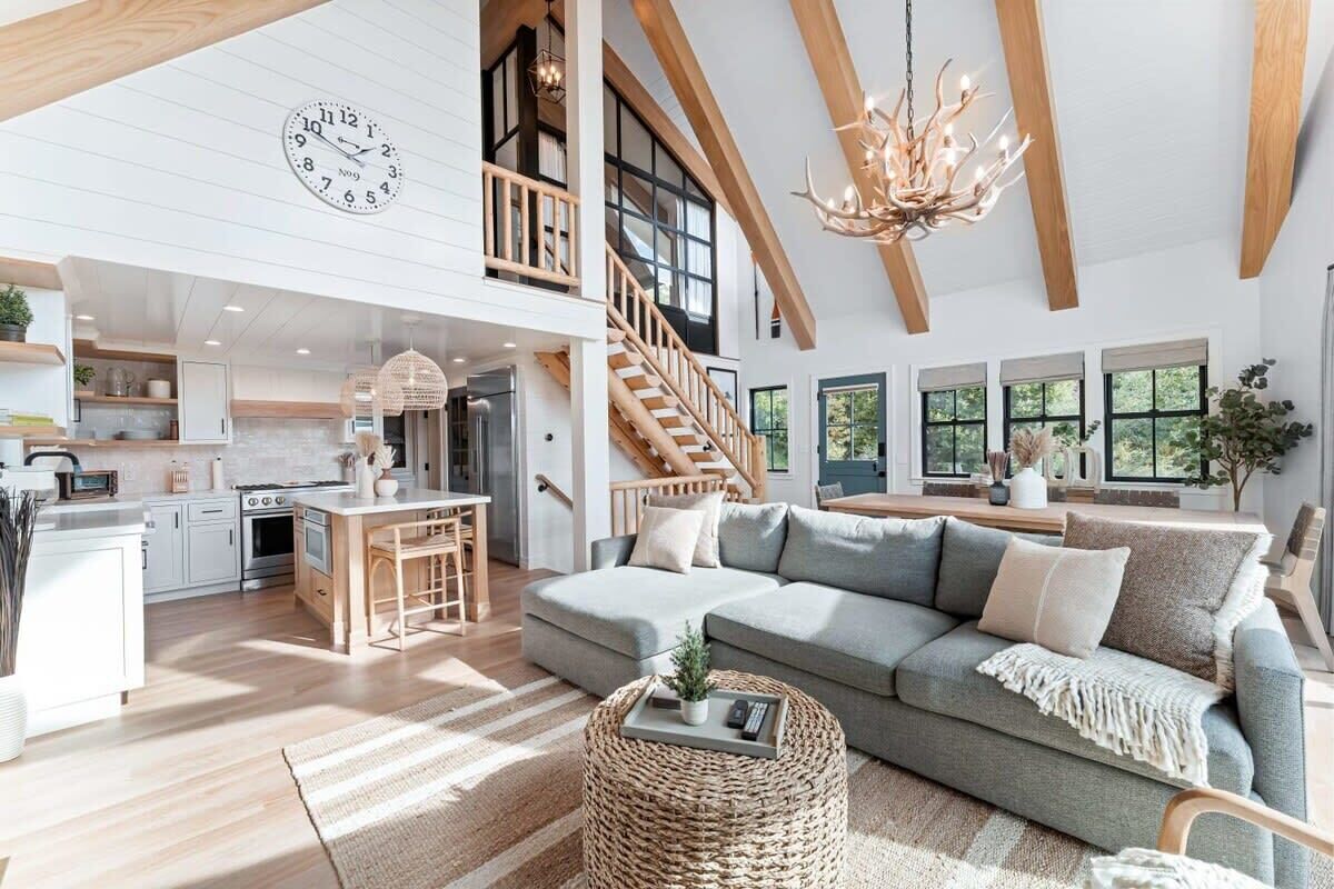 A spacious living area with a large sofa, a dining table, and a kitchen in the background.