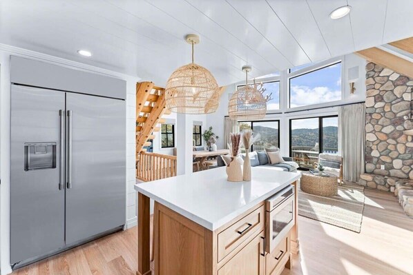 Una cocina moderna con una isla grande, refrigerador de acero inoxidable y una pared decorativa de piedra.