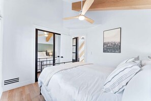 A bedroom with a large bed, a ceiling fan, a framed picture on the wall, and a view of a balcony. - Majestic Lakeview Lodge w/ Private Dock (Lake Arrowhead)