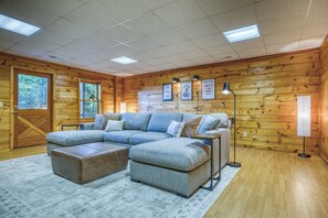 A cozy cabin interior with a sectional sofa, a wooden floor, and a ceiling with recessed lighting. - Thoughtfully updated cabin with mountain views, screened decks, hot tub (Blue Ridge)