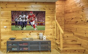 Ein Holzinnenraum mit einem an der Wand befestigten Fernseher, der ein Fußballspiel zeigt.