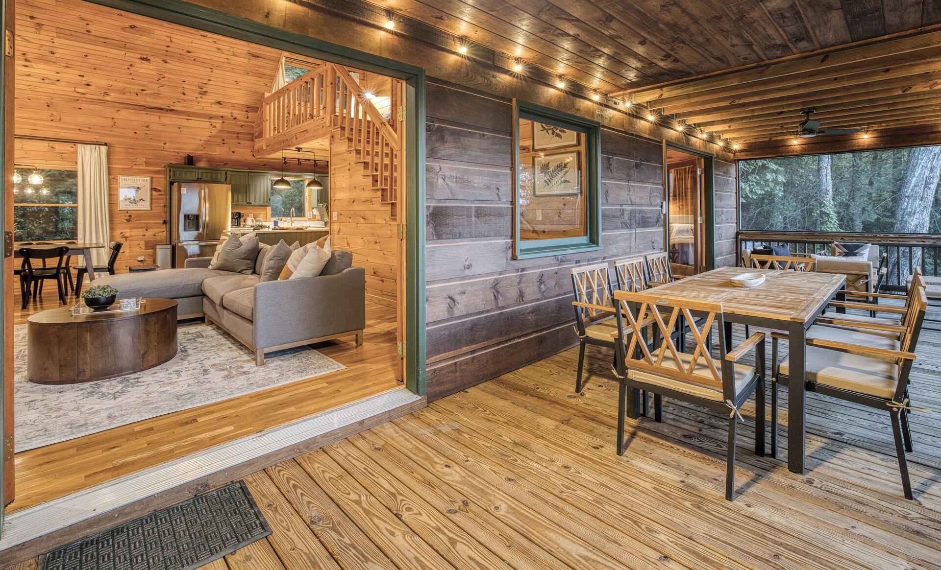 A wooden cabin interior with a living room, dining area, and staircase.
