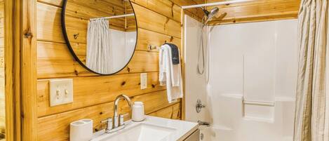 Une salle de bain aux murs lambrissés, équipée d’un lavabo, d’un miroir et de toilettes.