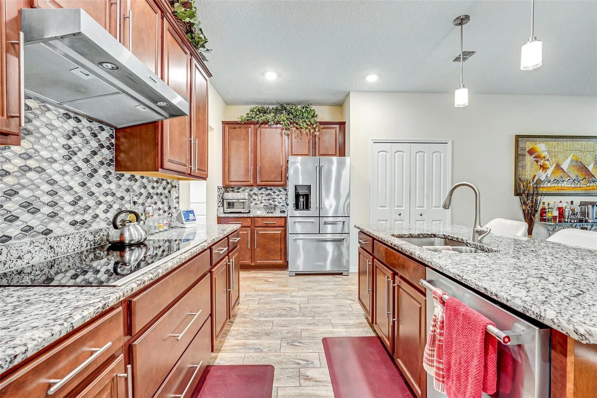 A modern kitchen with granite countertops, stainless steel appliances, wooden cabinets, and a central island.