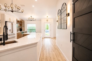 A modern kitchen with a central island, pendant lighting, and a view to the outside. - Modern Botanical Retreat near Beaches, Warm Mineral Springs & Sarasota Memorial (North Port)
