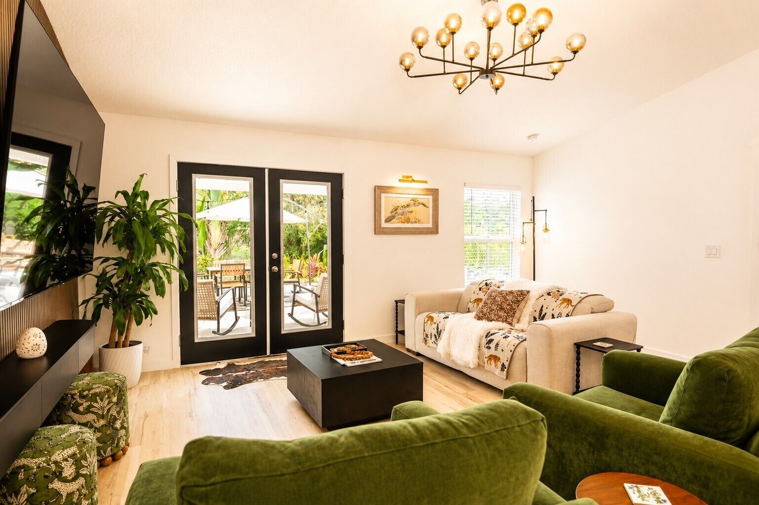 A living room with a sofa, a coffee table, a plant, and a dining area with chairs and a table.