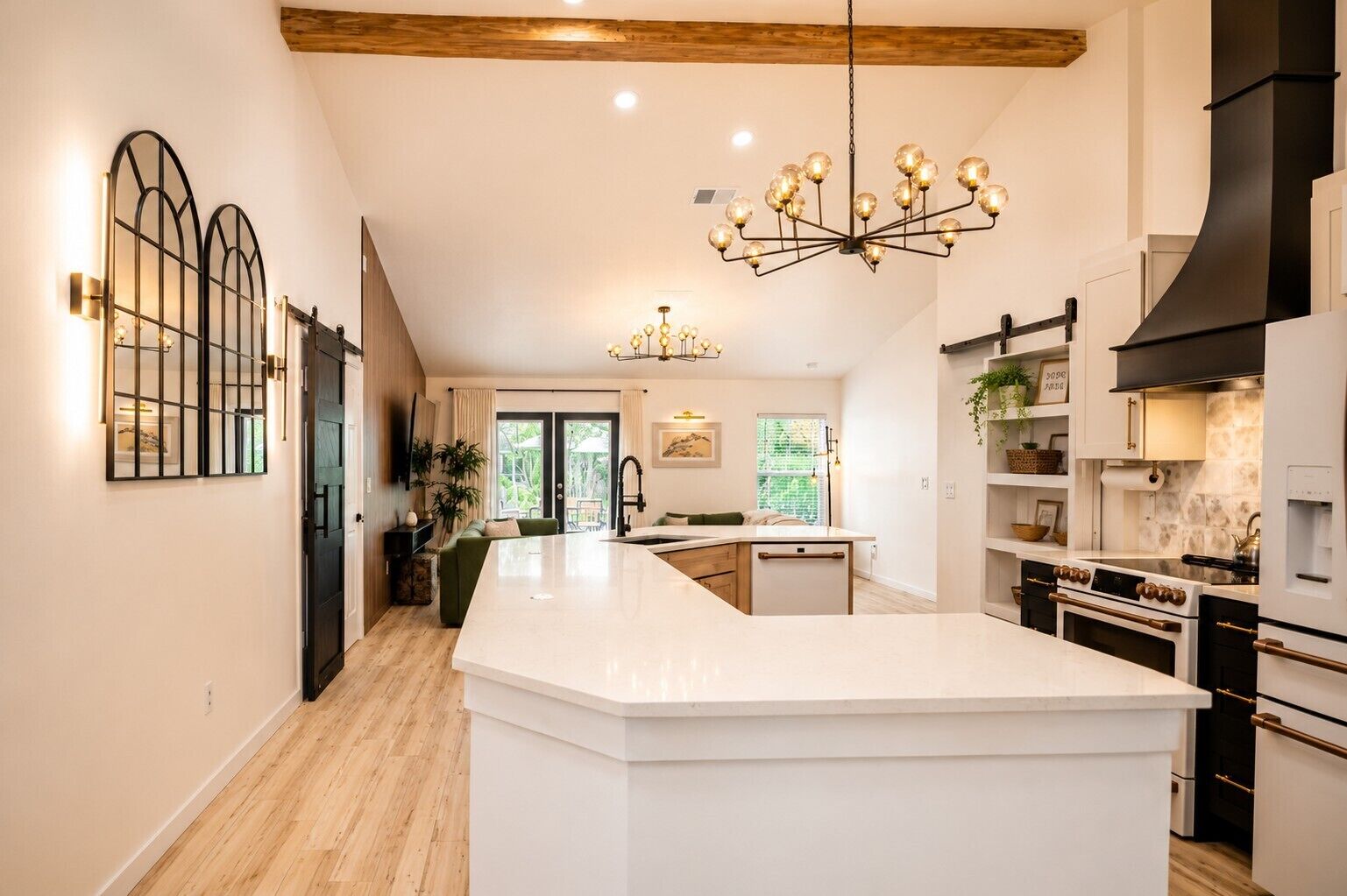 A modern kitchen with a central island, built-in appliances, and a large chandelier.