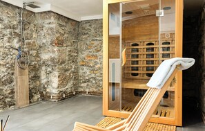 A stone-walled bathroom with a wooden sauna bench and a glass-enclosed shower area. - Stunning home in Moravice with sauna (Moravice)