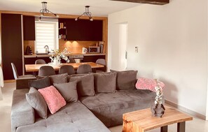 A modern living room with a grey sectional sofa, a wooden coffee table, and a dining area with a wooden table and chairs. - Stunning home in Moravice with sauna (Moravice)