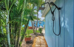 A pathway leading to a blue building with a shower mounted on the wall. - 3 min walk to the best sunsets on the beach! (St. Pete Beach)