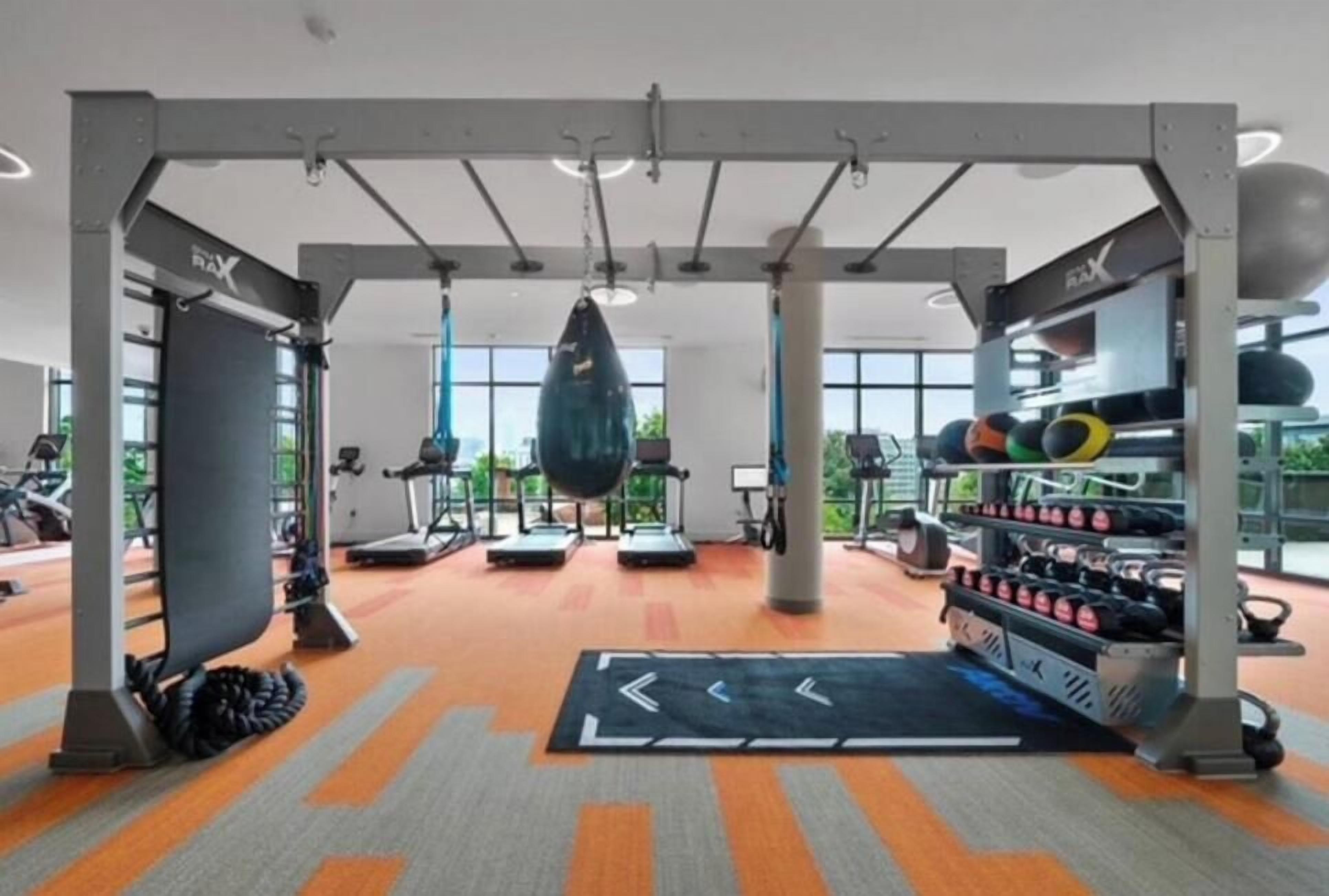A gym with exercise equipment, a punching bag, and a weight rack.