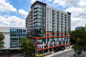 A multi-story building with a modern architectural design, featuring a mix of glass and concrete facades, and a prominent red accent on the lower level. - Luxe Skyline in Midtown Atlanta (Atlanta)