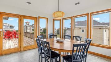 A dining area with a round table and chairs, large windows, and a view of the neighborhood.