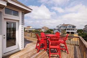 A wooden deck with a table and chairs, overlooking a residential area with houses.