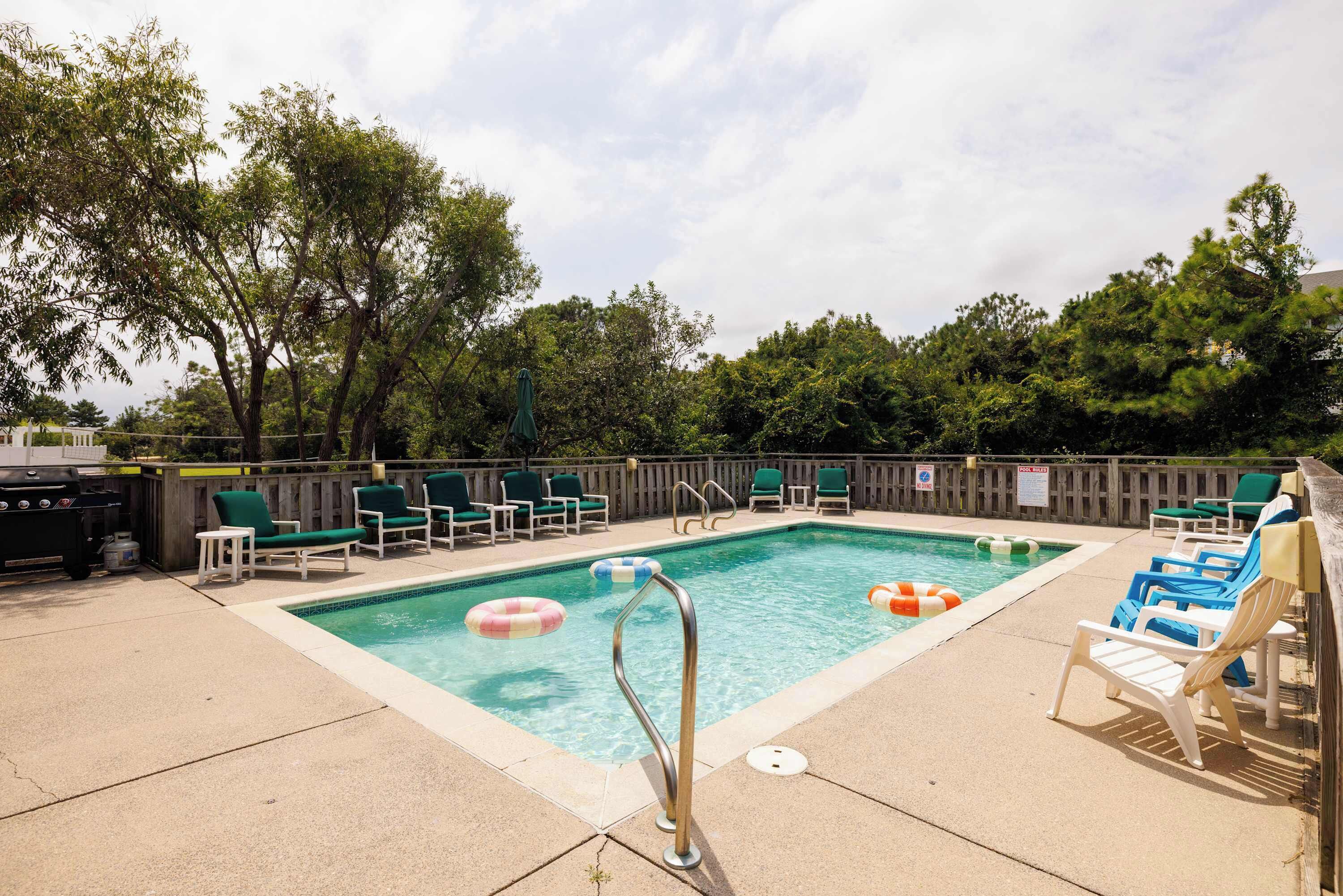 A swimming pool with lounge chairs and a barbecue grill.
