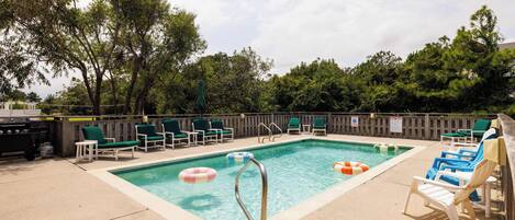 Une piscine avec des chaises longues et un barbecue.