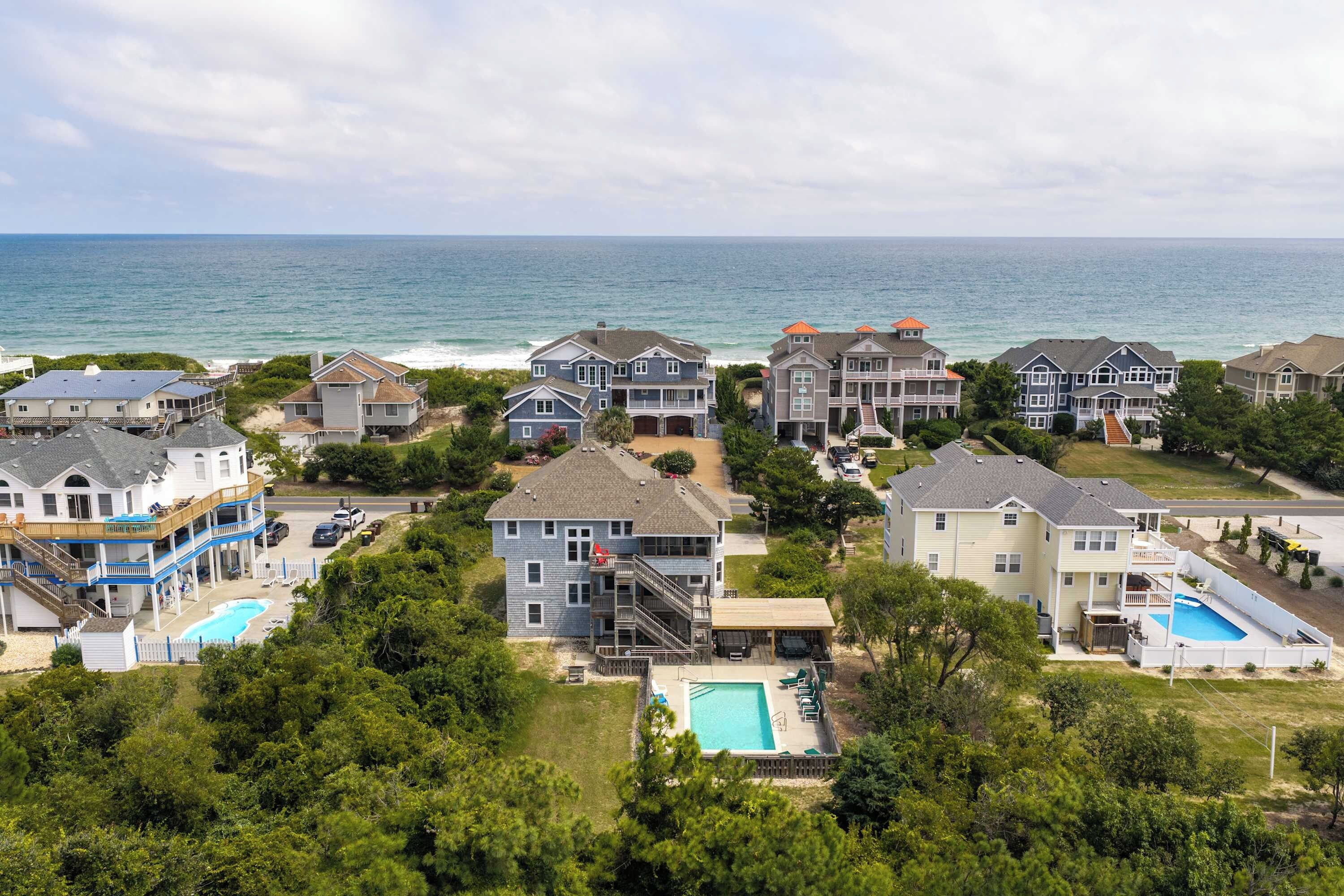 A coastal residential area with multiple houses, a swimming pool, and a view of the ocean.