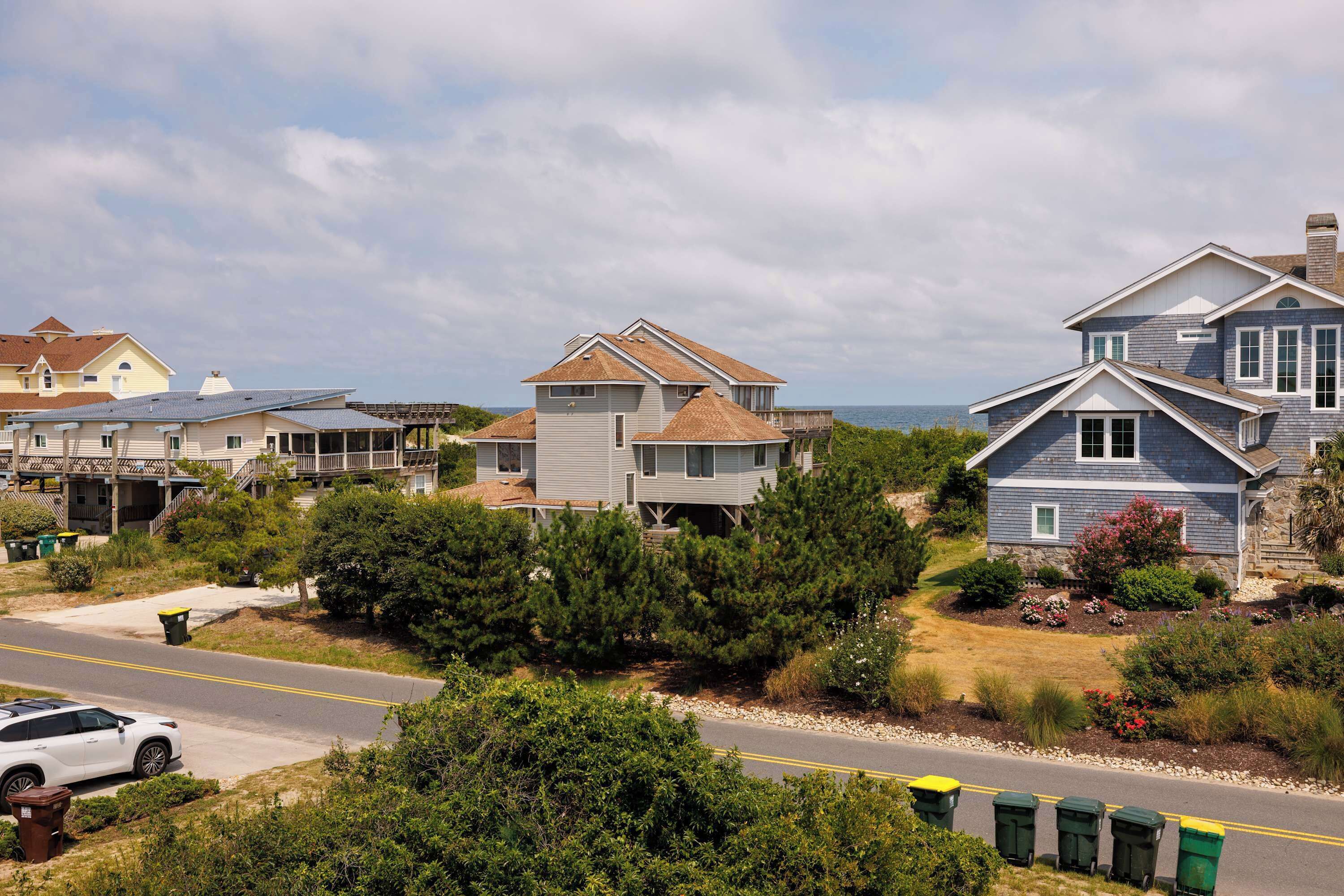 A coastal residential area with houses, a road, and a white car.