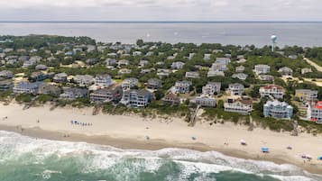 Una zona residenziale sul litorale con case affacciate sulla spiaggia, una spiaggia sabbiosa e onde oceaniche.