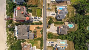 Vista aerea di una zona residenziale con case, una spiaggia e una strada.