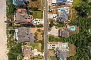 An aerial view of a residential area with houses, a beach, and a road.