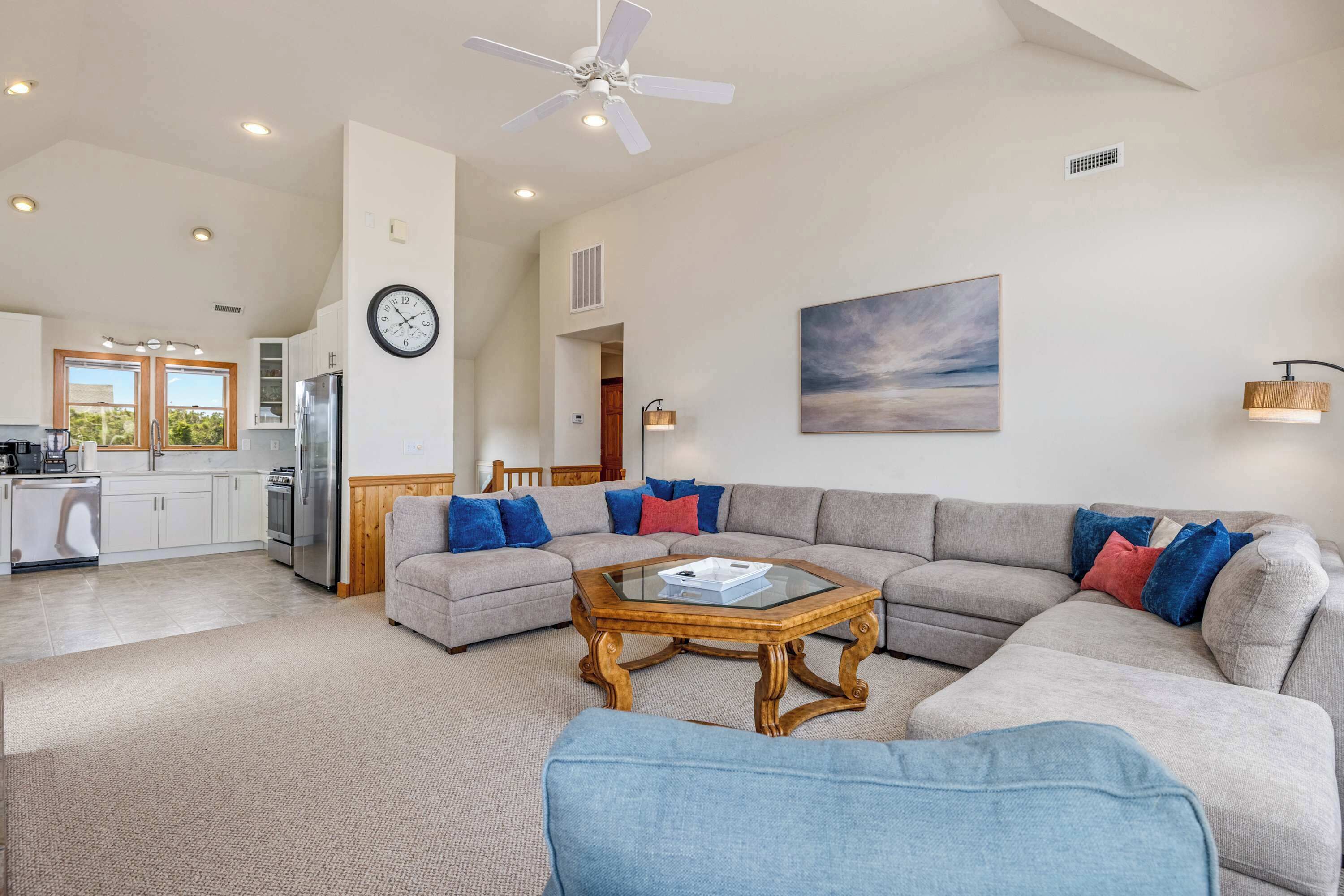 A spacious living area with a sectional sofa, a coffee table, and a ceiling fan.