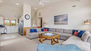 A spacious living area with a sectional sofa, a coffee table, and a ceiling fan.