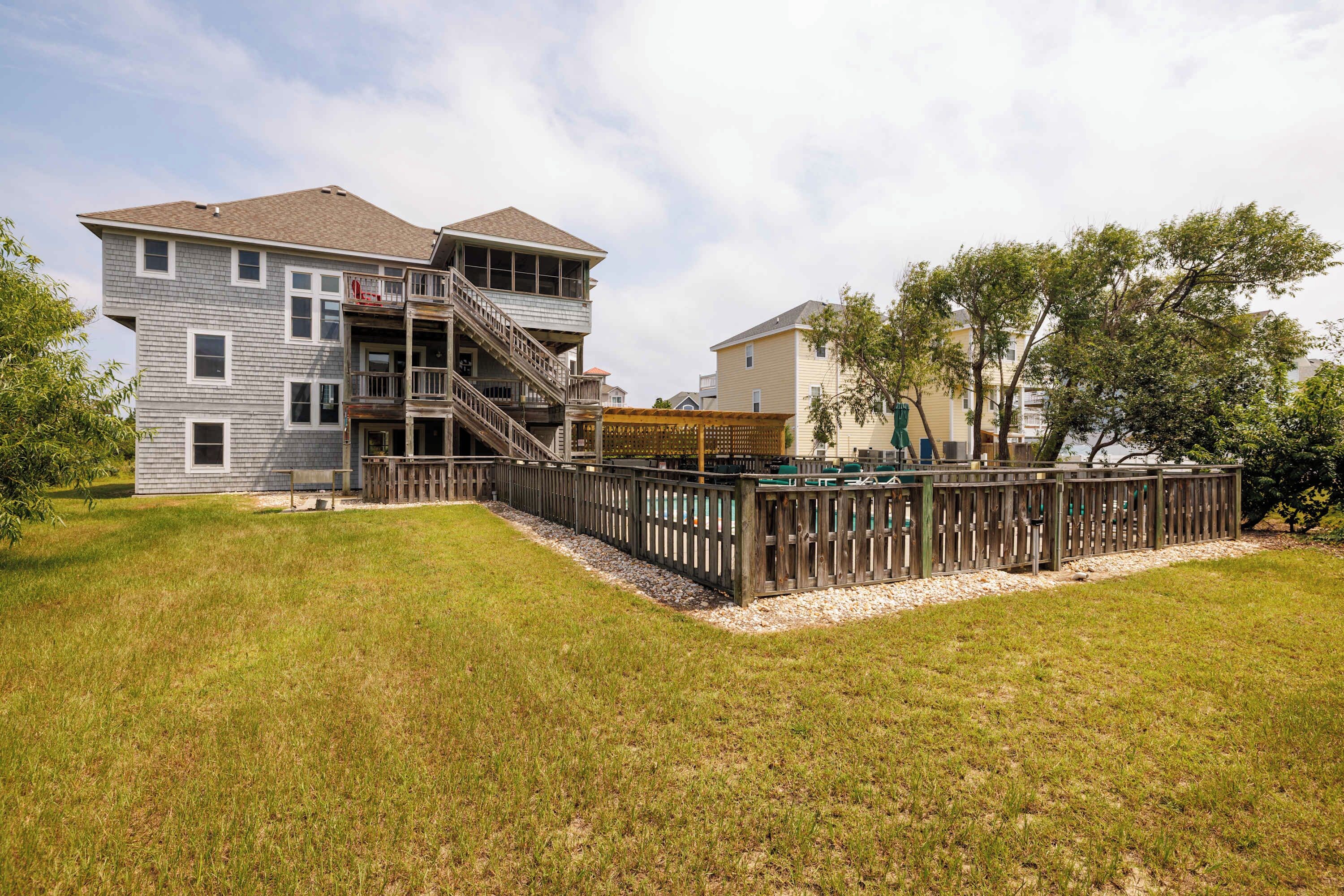 A two-story house with a wooden deck and a fenced backyard.