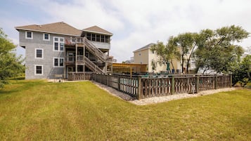 A two-story house with a wooden deck and a fenced backyard.