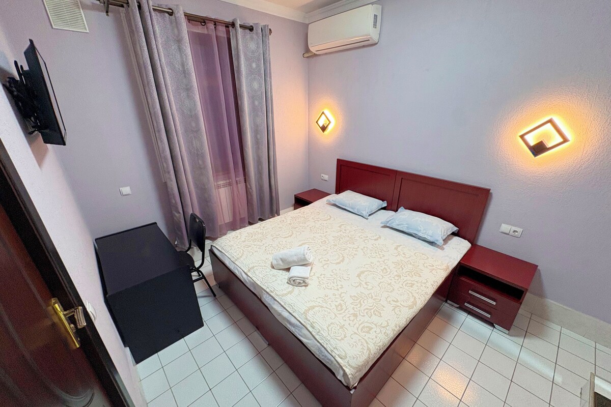 Una camera da letto con un letto, comodini, una scrivania e un condizionatore d'aria.