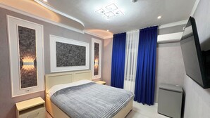 Una camera da letto moderna con un letto, comodini, una TV e una piccola credenza.