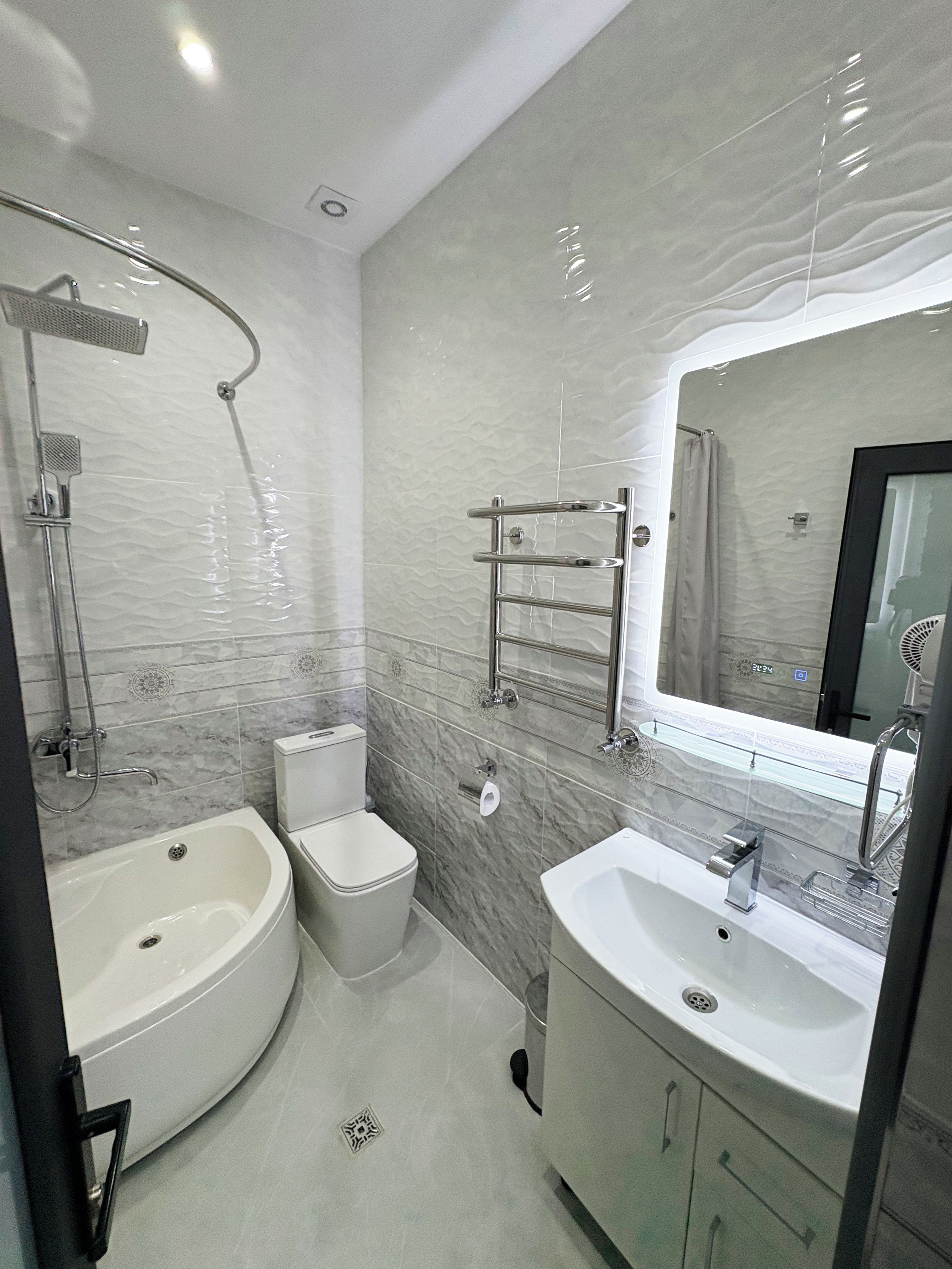 A modern bathroom with a curved bathtub, a toilet, a sink, and a shower.