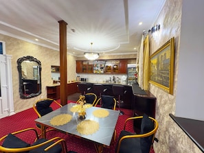 A dining area with a table set for four, surrounded by chairs, a bar area with a counter, and a large mirror on the wall. - Guest-House Grand (Tashkent)