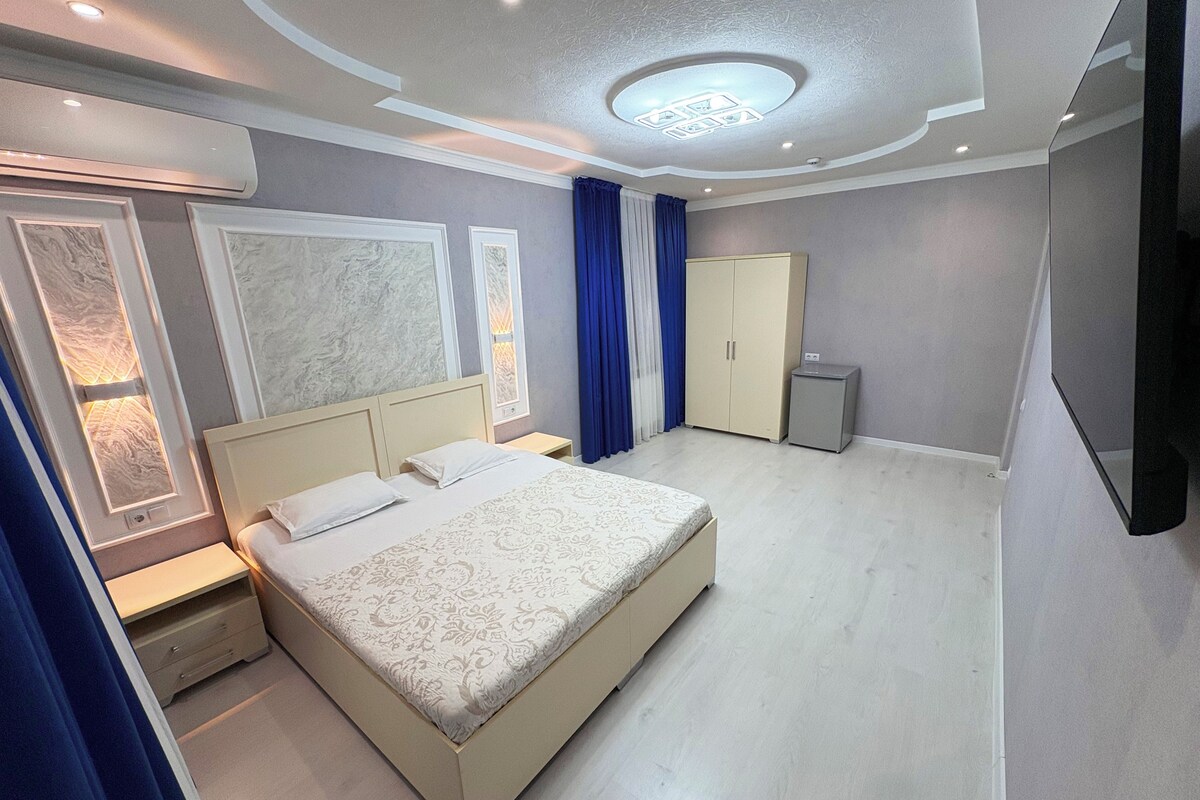 Una camera da letto moderna con un letto grande, comodini, un armadio e un lampadario.
