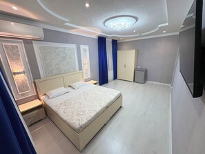 A modern bedroom with a large bed, bedside tables, a wardrobe, and a ceiling light fixture. - Guest-House Grand (Tashkent)