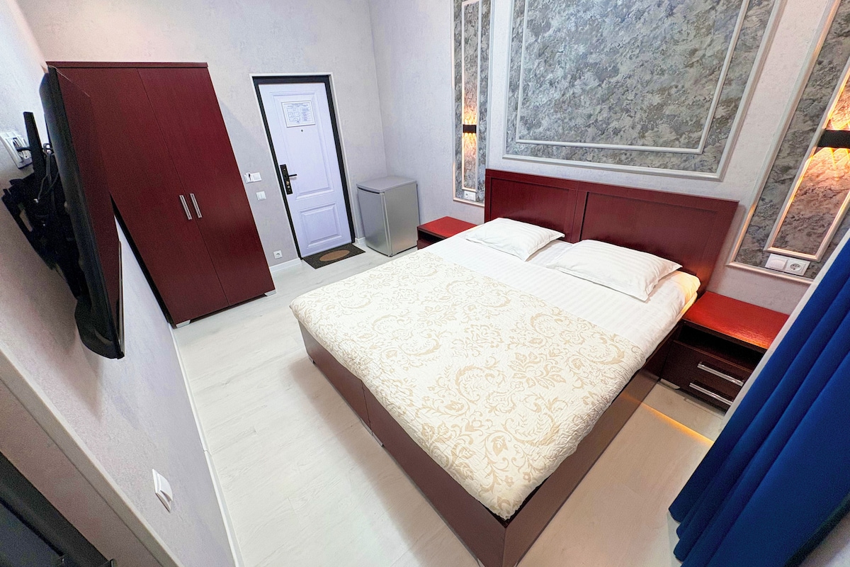 Una camera d'albergo con un letto grande, un armadio, una scrivania e un piccolo mobiletto.