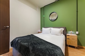 A bedroom with a bed, a bedside table, a nightstand, a lamp, and a mirror on the wall. - 2-Bedroom Apartment with Patio | Polanco | Relax (Ciudad de México)