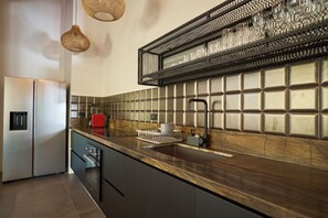 Et moderne køkken med et rustfrit stål køleskab, en indbygget ovn, en vask med hane og en bordplade med en opvaskestativ.