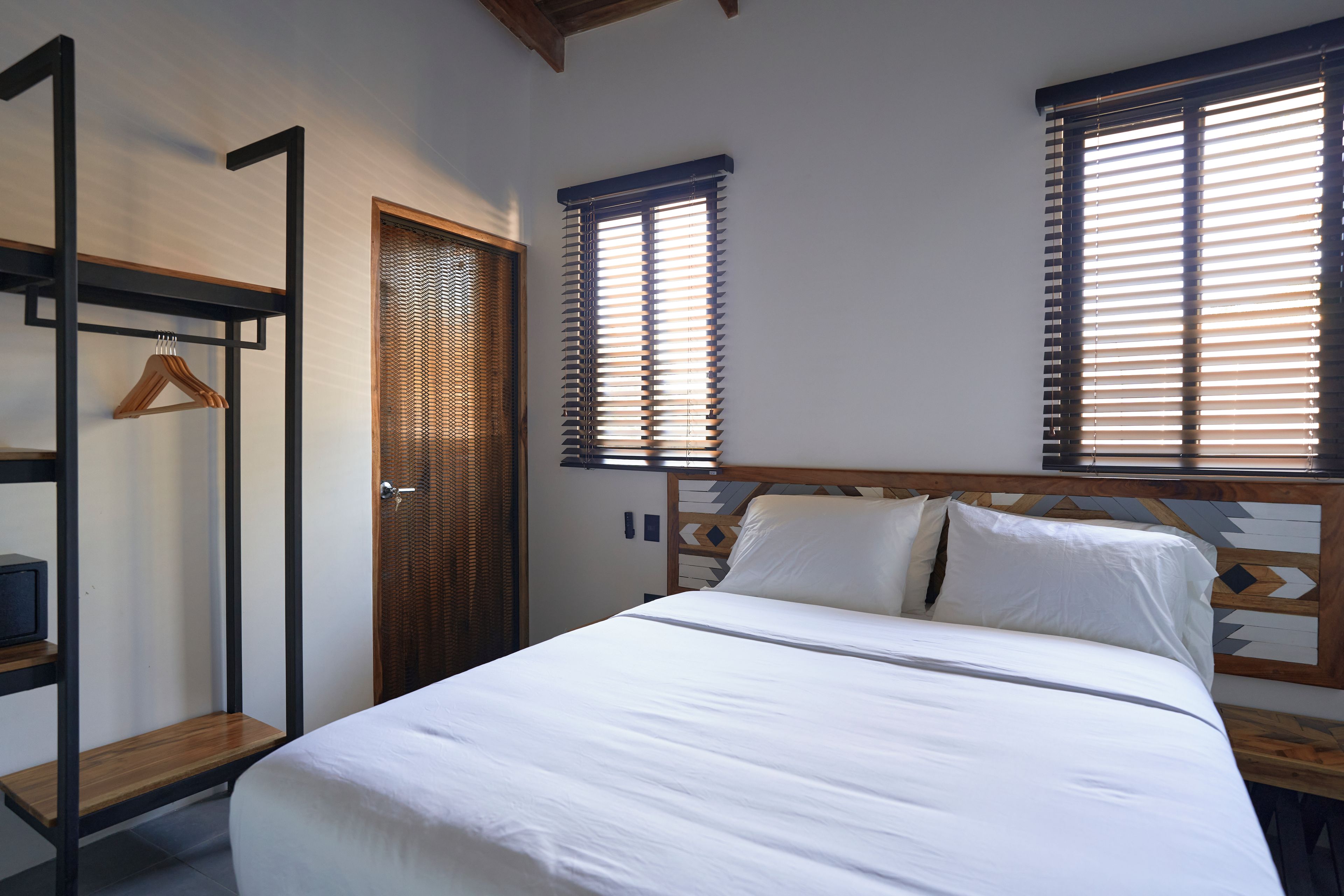 A bedroom with a bed, a wooden wardrobe, and a door with a keyhole.
