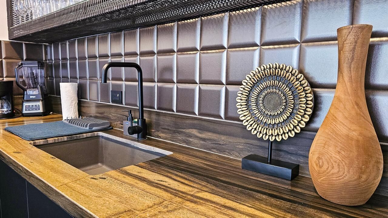 Une cuisine au design moderne, comprenant un évier, un mixeur et un vase décoratif en bois.